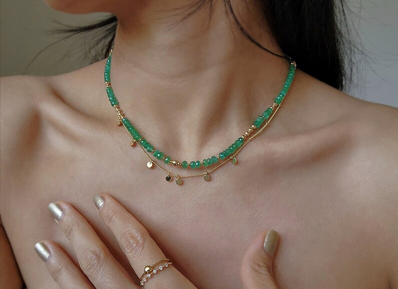 May include: A gold chain necklace with a layered strand of green gemstone beads and small gold disc charms.