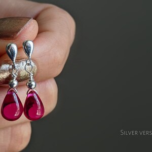 May include: A pair of silver dangle earrings with teardrop-shaped pink glass beads.