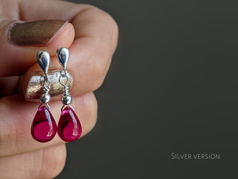 May include: A pair of silver dangle earrings with teardrop-shaped pink glass beads.