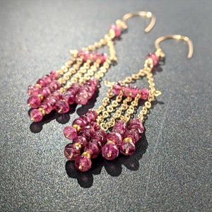 Puede incluir: Pendientes de oro con un dise&ntilde;o en cascada de piedras preciosas rosas. Los pendientes son largos y colgantes, con varias hileras de peque&ntilde;as piedras rosas.