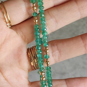 May include: A double strand necklace with green emerald beads and gold beads.