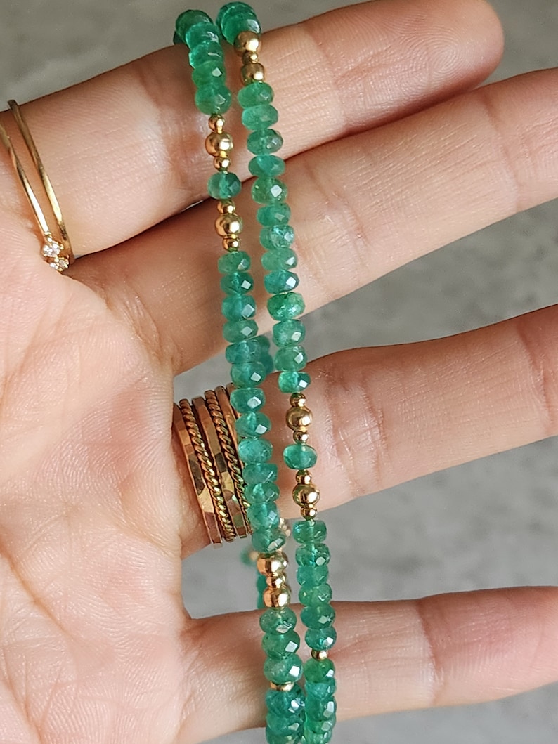 May include: A double strand necklace with green emerald beads and gold beads.