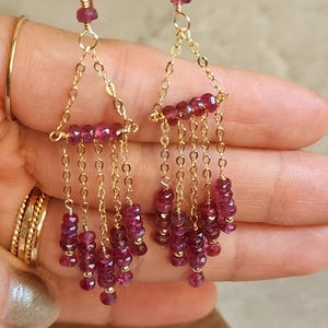 Puede incluir: Pendientes de oro con un dise&ntilde;o de l&aacute;grima de piedra preciosa rosa. Los pendientes presentan una cadena delicada con m&uacute;ltiples piedras preciosas rosas.