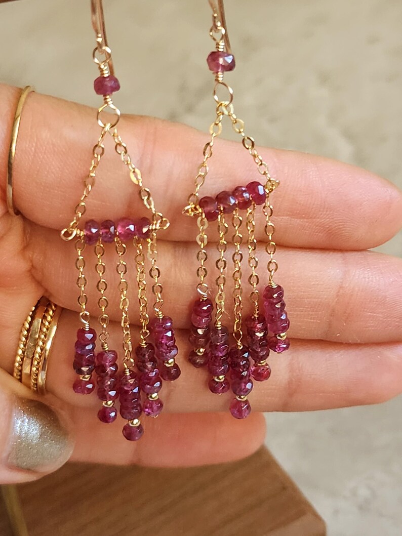 Puede incluir: Pendientes de oro con un dise&ntilde;o de l&aacute;grima de piedra preciosa rosa. Los pendientes presentan una cadena delicada con m&uacute;ltiples piedras preciosas rosas.