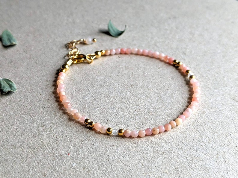 May include: A delicate bracelet made with small pink opal beads and gold accents.