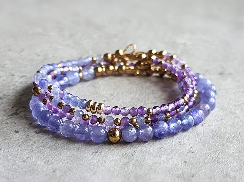 May include: A multi-strand bracelet with amethyst and blue gemstone beads, separated by gold beads.