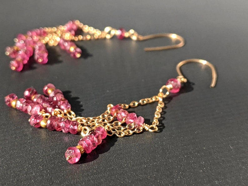 Puede incluir: Un par de pendientes de oro con cuentas de piedras preciosas rosas. Los pendientes tienen un dise&ntilde;o de cadena con m&uacute;ltiples hileras de cuentas.