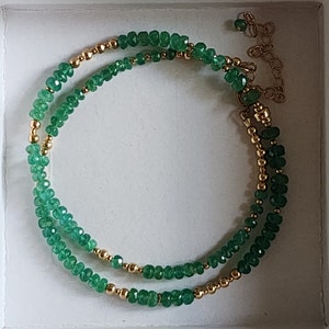 May include: A double strand bracelet with green gemstone beads and gold beads. The bracelet has a gold clasp.