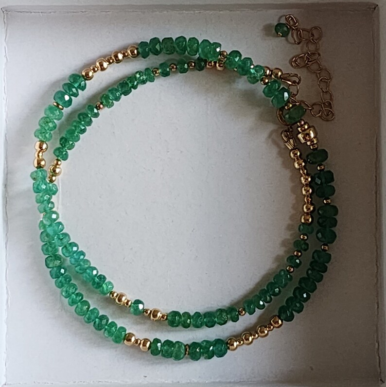 May include: A double strand bracelet with green gemstone beads and gold beads. The bracelet has a gold clasp.