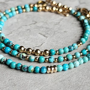 May include: Three layered turquoise and gold beaded bracelets. The turquoise beads are a mix of light and dark blue shades. The gold beads are small and round.