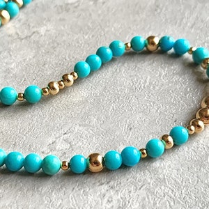 May include: A turquoise and gold beaded bracelet. The bracelet is made with small, round turquoise beads and gold beads.