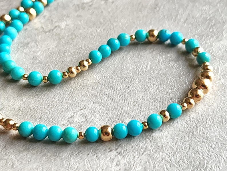 May include: A turquoise and gold beaded bracelet. The bracelet is made with small, round turquoise beads and gold beads.