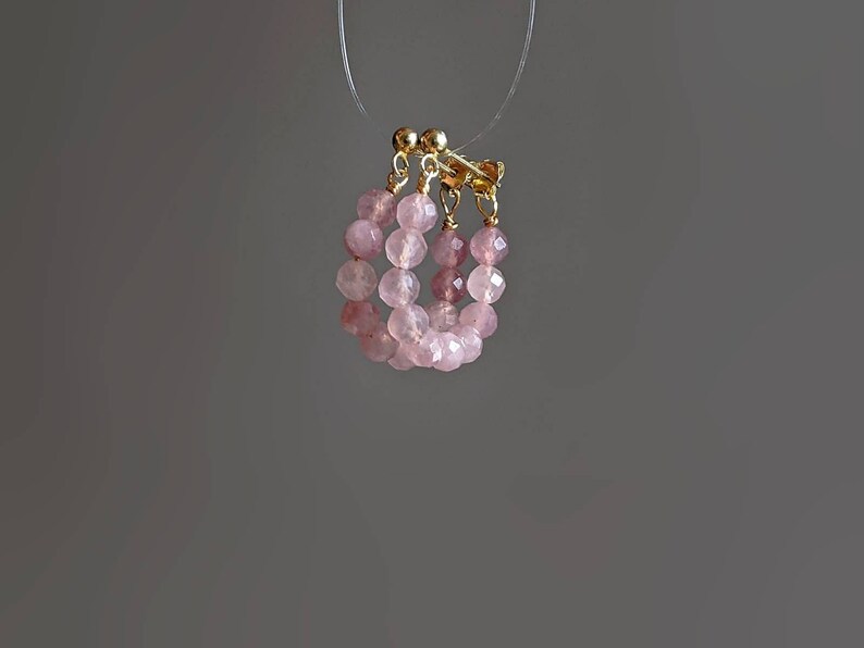 May include: A pair of pink and gold hoop earrings made with faceted rose quartz beads.