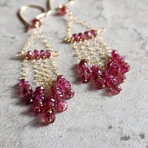Puede incluir: Pendientes de oro con m&uacute;ltiples cadenas de peque&ntilde;as piedras preciosas rosas.
