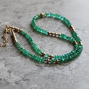 May include: A double strand necklace made with green emerald beads and gold beads.