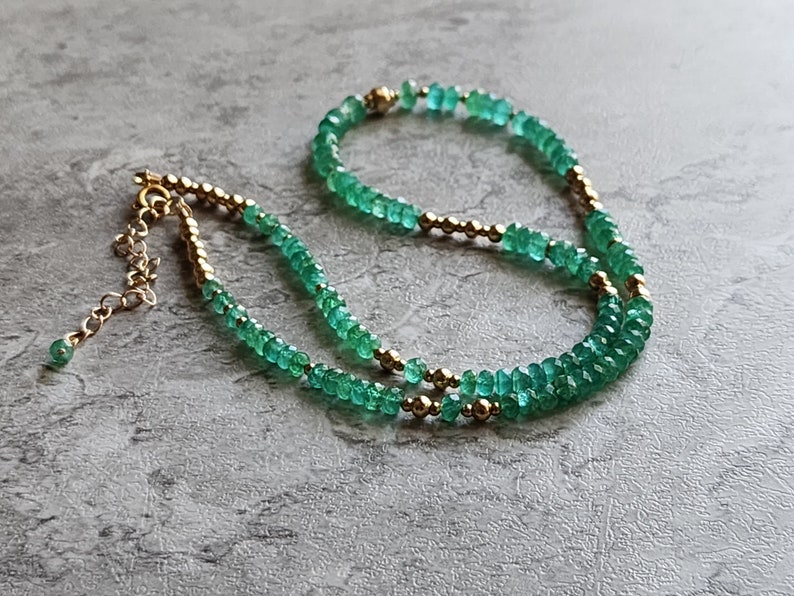 May include: A double strand necklace made with green emerald beads and gold beads.