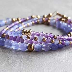 May include: A multi-strand bracelet with purple and blue gemstone beads and gold spacers.
