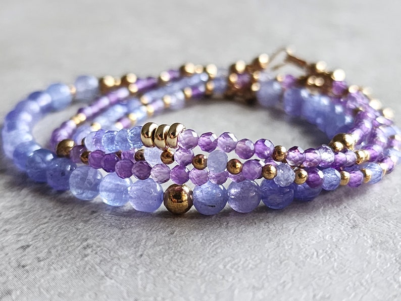 May include: A multi-strand bracelet with purple and blue gemstone beads and gold spacers.