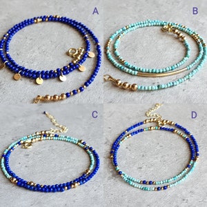 May include: Four different styles of layered beaded necklaces with gold accents. The necklaces are made with blue and turquoise beads.