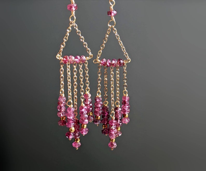 Puede incluir: Un par de pendientes de oro con cuentas de piedras preciosas rosas. Los pendientes tienen un dise&ntilde;o triangular con m&uacute;ltiples hilos de cuentas que cuelgan de la parte inferior.
