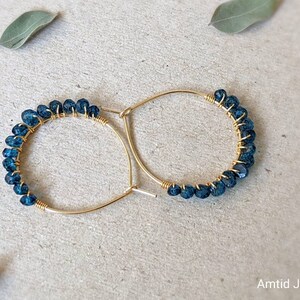 May include: Gold hoop earrings with a row of dark blue gemstone beads.