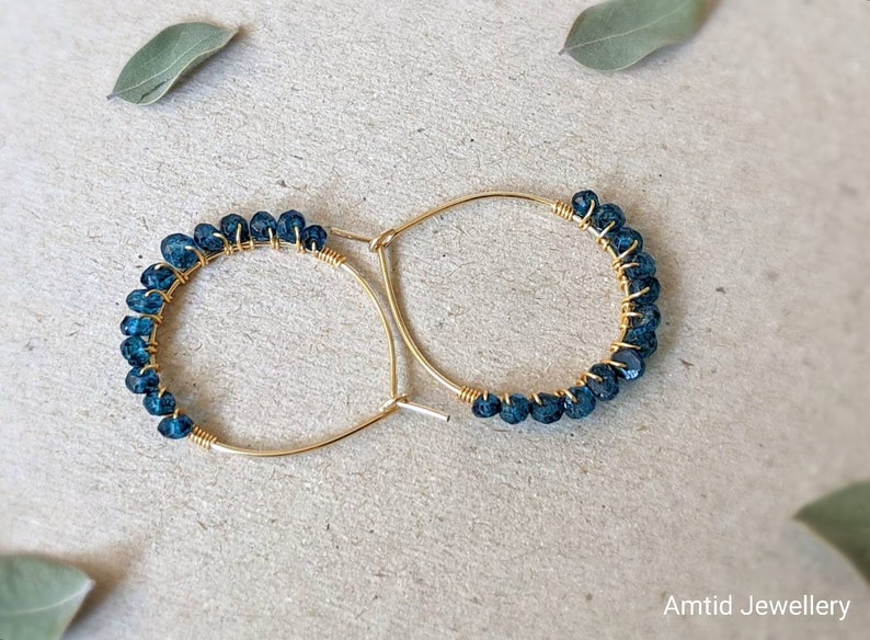 May include: Gold hoop earrings with a row of dark blue gemstone beads.