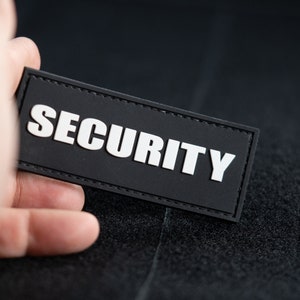 May include: Black patch with white stitching around the edges. The patch says "SECURITY" in white capital letters.