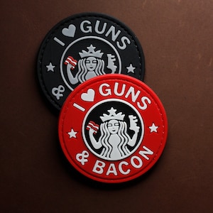 Può includere: Due toppe rotonde con un'immagine in bianco e nero di una sirena che tiene una pistola e una fetta di pancetta. Il testo sulle toppe recita "I ♥ GUNS & BACON".
