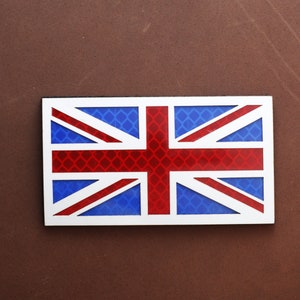 May include: A white, red, and blue Union Jack flag with a reflective, grid-like pattern. The flag is made of a durable material and is perfect for displaying your national pride.