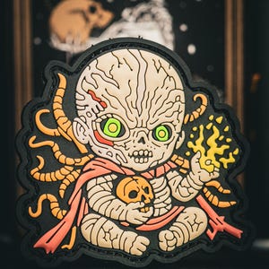 May include: A patch featuring a stylized, undead baby-like figure with green eyes, holding a skull and a flame. The design includes orange tentacles, a red sash, and a black border.