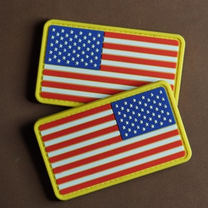 May include: Two yellow-bordered patches with the American flag design. The flag is red, white, and blue with a blue field of stars.