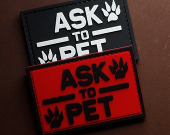 以下が含まれることがあります： 「Ask to Pet」という文字と肉球のプリントが施された、黒と白の2つのパッチ。上のパッチは黒地に白文字、下のパッチは赤地に黒文字です。