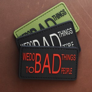 Può includere: Tre toppe nere e verdi con testo bianco e rosso. La toppa superiore dice "We Do Bad Things". La toppa centrale dice "We Do Bad Things To People". La toppa inferiore dice "We Do Bad Things To People".