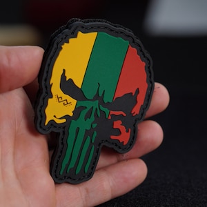 May include: A black skull patch with a green, yellow, and red design. The skull is outlined in black and has a white skull and crossbones design on the forehead.