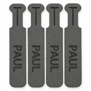 May include: Four identical dark gray fabric labels arranged vertically. Each rectangular label features a rounded top with a T-shaped cutout and the name PAUL embossed in capital letters in the center of the textured, woven material surface.