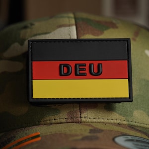 May include: A black, red and yellow German flag patch with the text "DEU" on a camouflage hat.