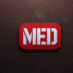 Könnte beinhalten: Roter rechteckiger Patch mit weißer reflektierender Aufschrift "MED".