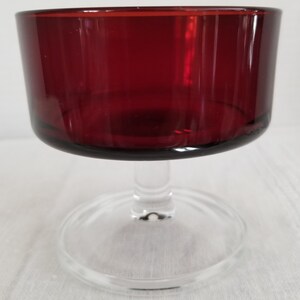 May include: A clear glass stemmed goblet with a deep red colored bowl. The goblet is perfect for serving cocktails or desserts.