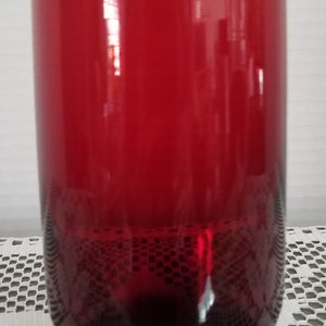 May include: A tall, clear glass with a red, ombre effect. The glass is empty and has a rounded bottom.