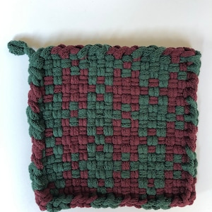 Könnte beinhalten: Ein gewebter Topflappen in Grün und Burgunderrot mit einem Fransenrand.