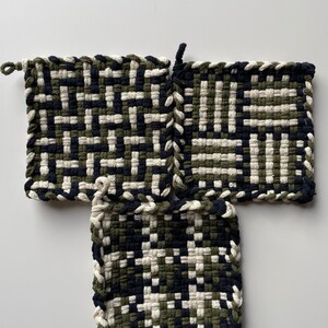 Könnte beinhalten: Drei quadratische gewebte Topflappen in einem geometrischen Muster aus schwarzem, weißem und grünem Garn.