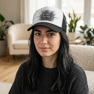 May include: Black and white trucker hat with the text "Eternal Ingrate" in a stylized font. The hat features a black brim and mesh back, with a white front panel displaying the graphic. The hat is worn by a person.