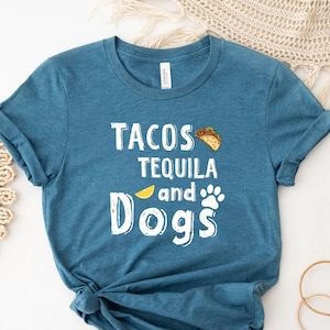 May include: A teal blue t-shirt with the text "Tacos Tequila and Dogs" in white lettering. A yellow lemon and a paw print are also included in the design. A taco is pictured above the text.