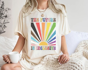 Peut inclure: Un t-shirt blanc avec un graphique arc-en-ciel et le texte "The Future is Inclusive".