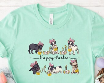 Puede incluir: Una camiseta verde claro con un gráfico de cinco bulldogs franceses con orejas de conejo y sosteniendo huevos de Pascua. El texto "Happy Easter" está impreso debajo de los perros.