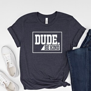 May include: A navy blue t-shirt with a white graphic that says "DUDE. BE KIND" in a box.