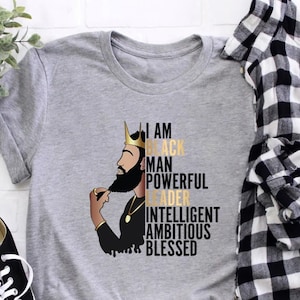 May include: Gray t-shirt with a black and gold illustration of a king with the text "I am Black Man Powerful Leader Intelligent Ambitious Blessed".