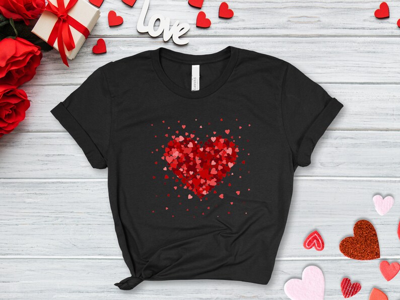 May include: Black t-shirt with a red heart made of smaller red hearts. The heart is surrounded by smaller red hearts scattered around it.