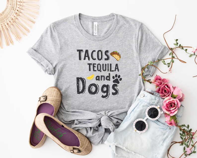 May include: Gray t-shirt with the text "Tacos Tequila and Dogs" in black lettering. The shirt has a yellow lemon slice and a paw print graphic.
