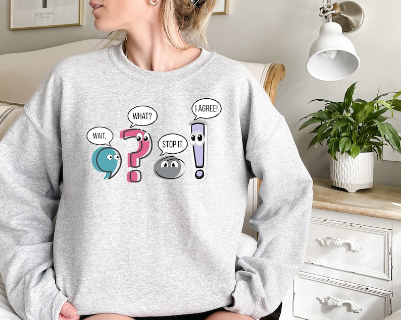 May include: Gray sweatshirt with a graphic of punctuation marks with faces and speech bubbles. The speech bubbles say "Wait", "What?", "Stop it", and "I agree!"
